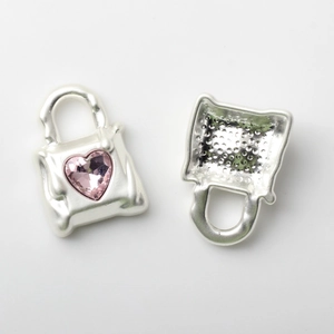 Detail of silver handbag pendant with pink heart crystal and honeycomb texture back