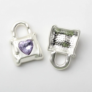 Macro view of silver handbag pendant featuring a purple heart-shaped rhinestone detail