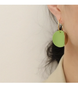 Gros plan de boucles d'oreilles rondes géométriques vert et or sur un modèle