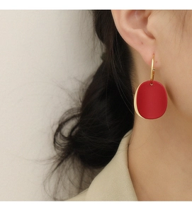 Gros plan d'une boucle d'oreille ovale rouge mat avec anneau doré sur un mannequin