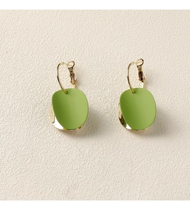 Vue détaillée des disques mats vert herbe et boucles d'oreilles dorées sur fond beige