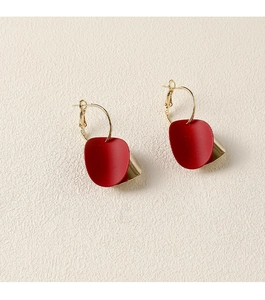 Détail de boucles d'oreilles pétales rouges mats avec couche en métal doré