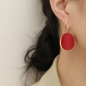 Boucles d'oreilles élégantes avec pendentif rouge mat et créoles dorées sur modèle