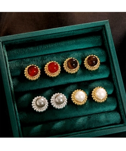 Nahaufnahme von Retro-Perlen- und Achat-Ohrsteckern in Gold- und Silberfassung auf Samt