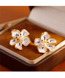 Detail of blue and white enamel flower earrings resting in a brown velvet jewelry box