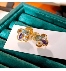 Dettaglio di orecchini a clip a quadrifoglio in smalto vintage con perle e zirconi