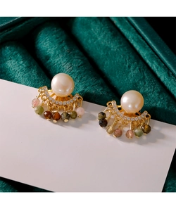 Detalle de pendientes de perlas con piedras de colores sobre un joyero de terciopelo verde