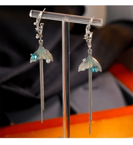 Dettaglio di orecchini a nappa con coda di pesce argento, stella blu e perle eleganti