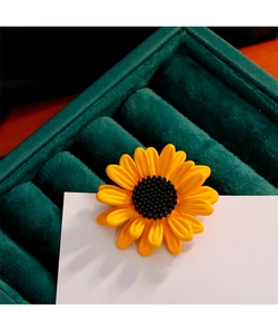 Détail macro de broche tournesol avec pétales jaunes sur boîte en velours vert