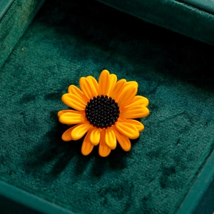 Élégante broche tournesol aux pétales jaunes sur une boîte cadeau en velours vert