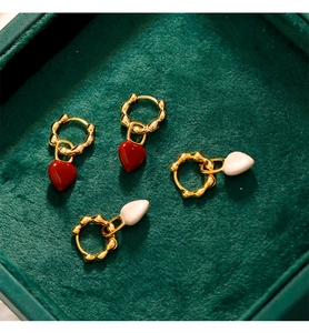 Vue détaillée des boucles d'oreilles cœur en émail rouge et blanc à anneaux dorés