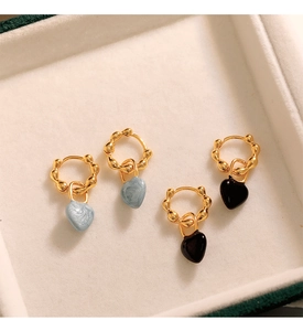 Détail de boucles d'oreilles cœur vintage en émail bleu et noir sur un plateau en velours