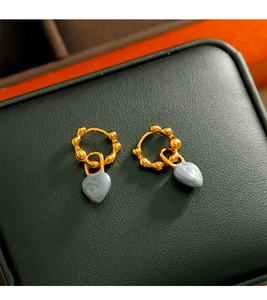 Détail de boucles d'oreilles cœur vintage avec émail marbré bleu sur boîte en cuir vert
