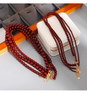 Détail d'un collier de perles multicouches avec perles rouge foncé et fermoirs dorés