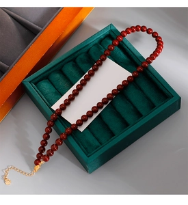 Détail du collier de perles rouges avec fermoir doré sur présentoir en velours