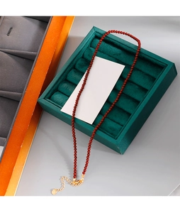 Détail d'un collier de perles rouges avec fermoir mousqueton doré et chaîne d'extension
