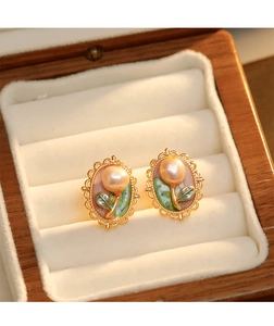 Détail de boucles d'oreilles perles ovales avec feuilles émaillées sur velours beige
