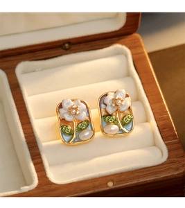 Détail macro de boucles d'oreilles émaillées vintage avec fleurs et perles en écrin bois