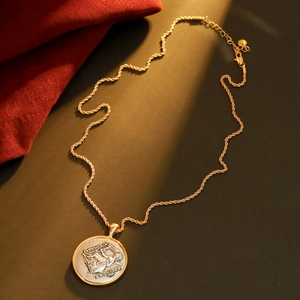 Vintage gold twist chain necklace with round embossed coin pendant on red velvet fabric
