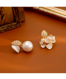 Détail des boucles d'oreilles asymétriques à fleurs et perles avec feuilles diamantées