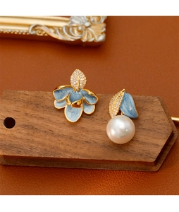 Détail de boucles d'oreilles asymétriques en émail avec perles et zircons micro-incrustés