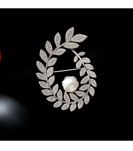 Macro detail of wheat ear brooch featuring a large pearl and sparkling zircon crystals
