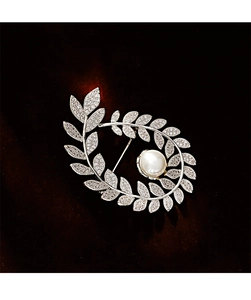 Close-up of a silver leaf brooch with sparkling crystals and a large white round pearl