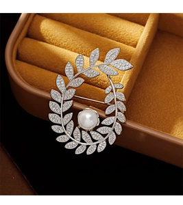 Close-up of a silver wheat ear brooch with sparkling zircons and a large central pearl
