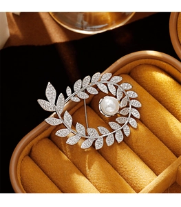 Macro shot of silver wheat brooch with pavé rhinestones and a large white pearl