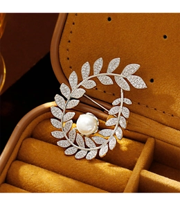 Detailed macro view of wheat ear brooch with sparkling zircons and a white pearl accent