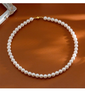 Détail de perles blanches rondes avec fermoir magnétique doré sur cuir marron
