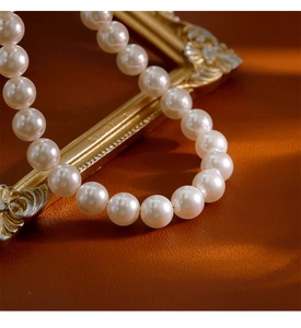 Macro d'un collier de perles blanches sur cadre doré vintage avec lumière chaude