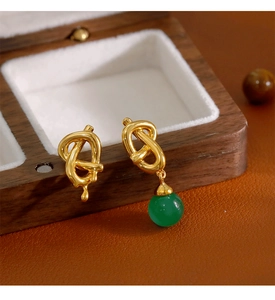 Détail de boucles d'oreilles asymétriques plaquées or avec calcédoine verte sur bois