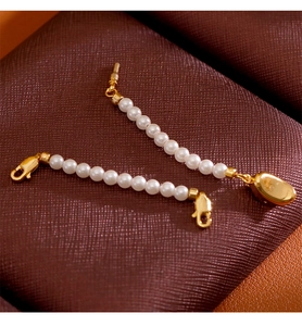 Détail macro de fermoirs mousquetons dorés et perles blanches sur cuir foncé