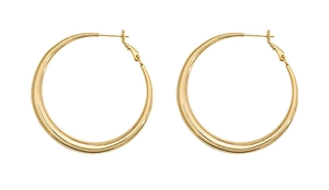 Détail de grandes boucles d'oreilles créoles dorées avec finition miroir polie et design rond