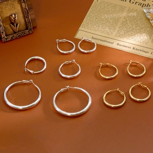Créoles classiques en or et argent de tailles variées sur fond en cuir texturé