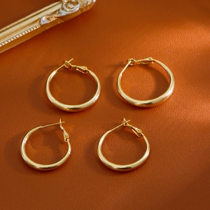 Boucles d'oreilles créoles dorées classiques sur fond en cuir marron vintage pour femme