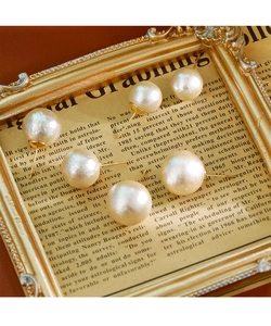 Vue détaillée de grandes boucles d'oreilles perles crème sur cadre doré vintage