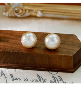 Gros plan de grandes boucles d'oreilles en perles blanc crème sur fond vintage et bois
