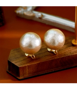 Vue macro de grandes boucles d'oreilles perles à texture soie sur socle bois
