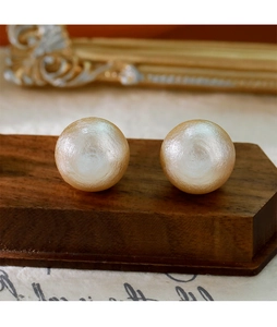 Gros plan détaillé de grandes boucles d'oreilles perles champagne sur support en bois