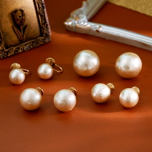 Boucles d'oreilles perles champagne vintage de tailles variées sur fond en cuir brun