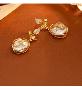 Detalle de pendientes de perlas barrocas con motivo de hoja de oro y circonitas