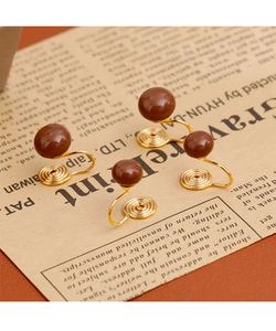 Détail de boucles d'oreilles clips à billes marron rétro sur fond de journal vintage