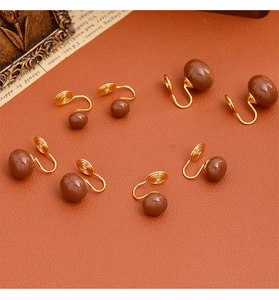 Clips d'oreilles perles brunes avec spirales dorées sur fond vintage élégant