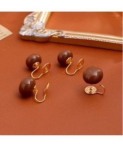 Détails macro de clips d'oreilles perles brunes avec fermoir spirale sur cuir