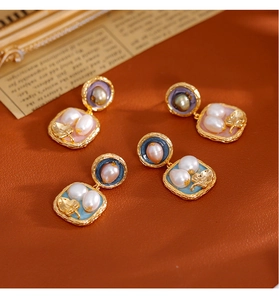 Dettaglio di orecchini vintage con perle d'acqua dolce e foglie d'oro su pelle