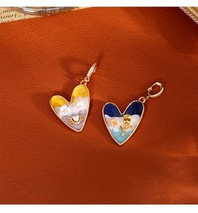 Vue détaillée de pendentifs cœur en émail avec bordure dorée et motifs de rose