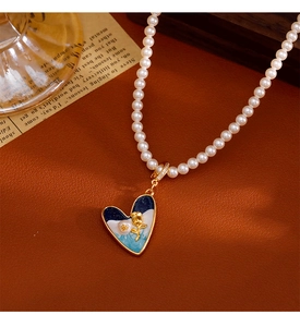 Détail d'un pendentif cœur en émail bleu avec rose dorée sur collier de perles baroques