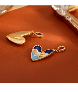 Détail macro du pendentif cœur avec émail bleu, relief rose et perle naturelle sur cuir
